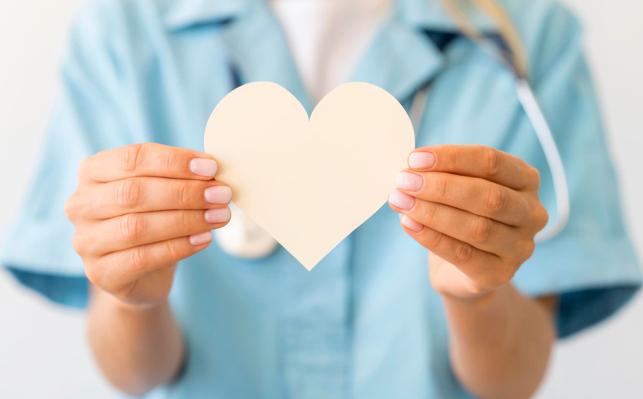 Photographie en couleur d'une professionnelle de santé tenant un coeur en papier dans la main.
