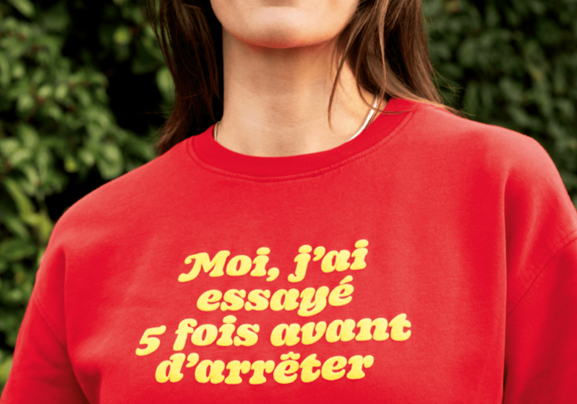 Sur l'image, nous pouvons voir le haut de corps d'une femme qui porte un pull avec une inscription : "Moi, j'ai essayé 5 fois avant d'arrêter" Cette image est tirée de la campagne de communication innovante du Ministère de la Santé dans la lutte en faveur de l'arrêt du tabac.