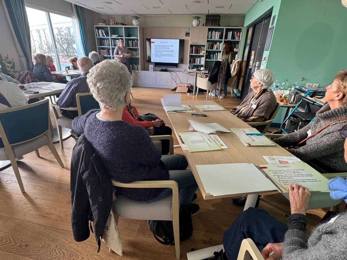 Sur l'image, nous pouvons voir un groupe de participants en train de regarder une présentation projetée sur un écran.